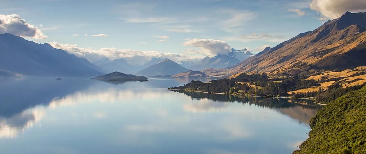 mountains and a still body of water, water is reflecting mountains and sky