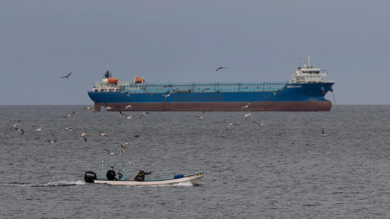 2026 年 3 月 25 日，美以与伊朗冲突期间，阿曼马斯喀特苏丹卡布斯港外，一艘渔船驶过停泊的船只。